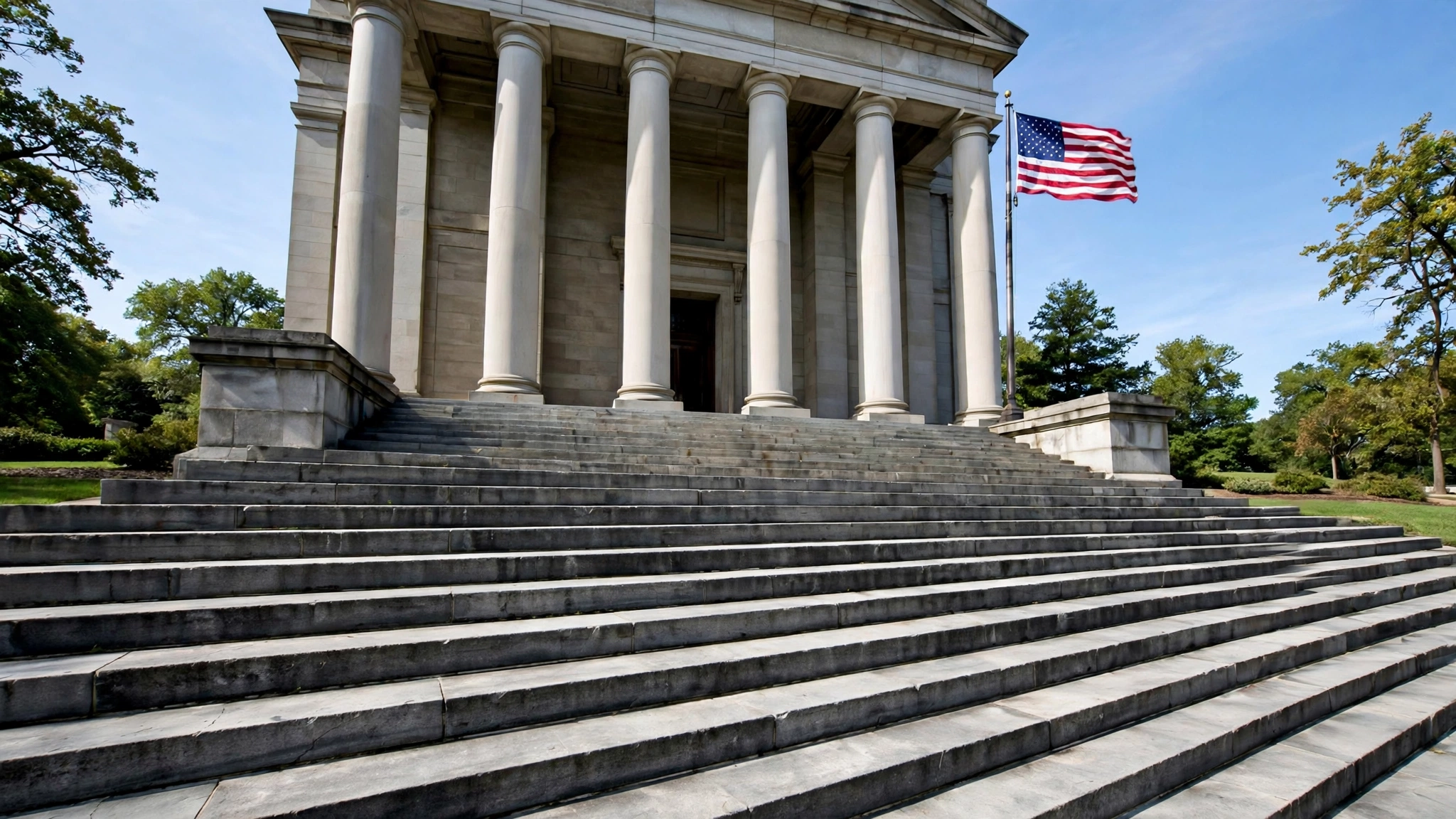 Stone courthouse steps and tall columns with an American flag beside the entrance
