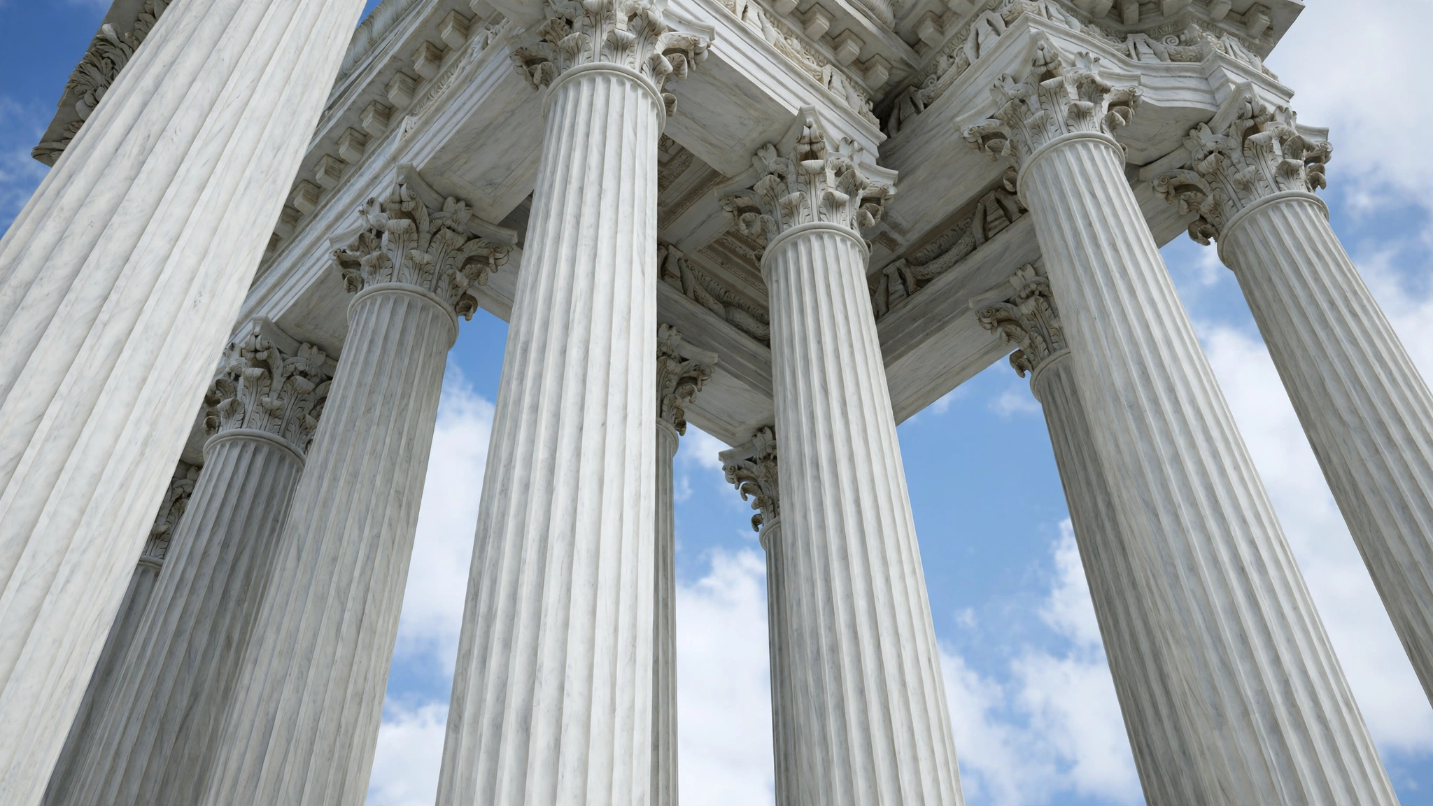 Close-up low-angle view of the fluted white marble columns of the U.S. Supreme Court building against a blue sky