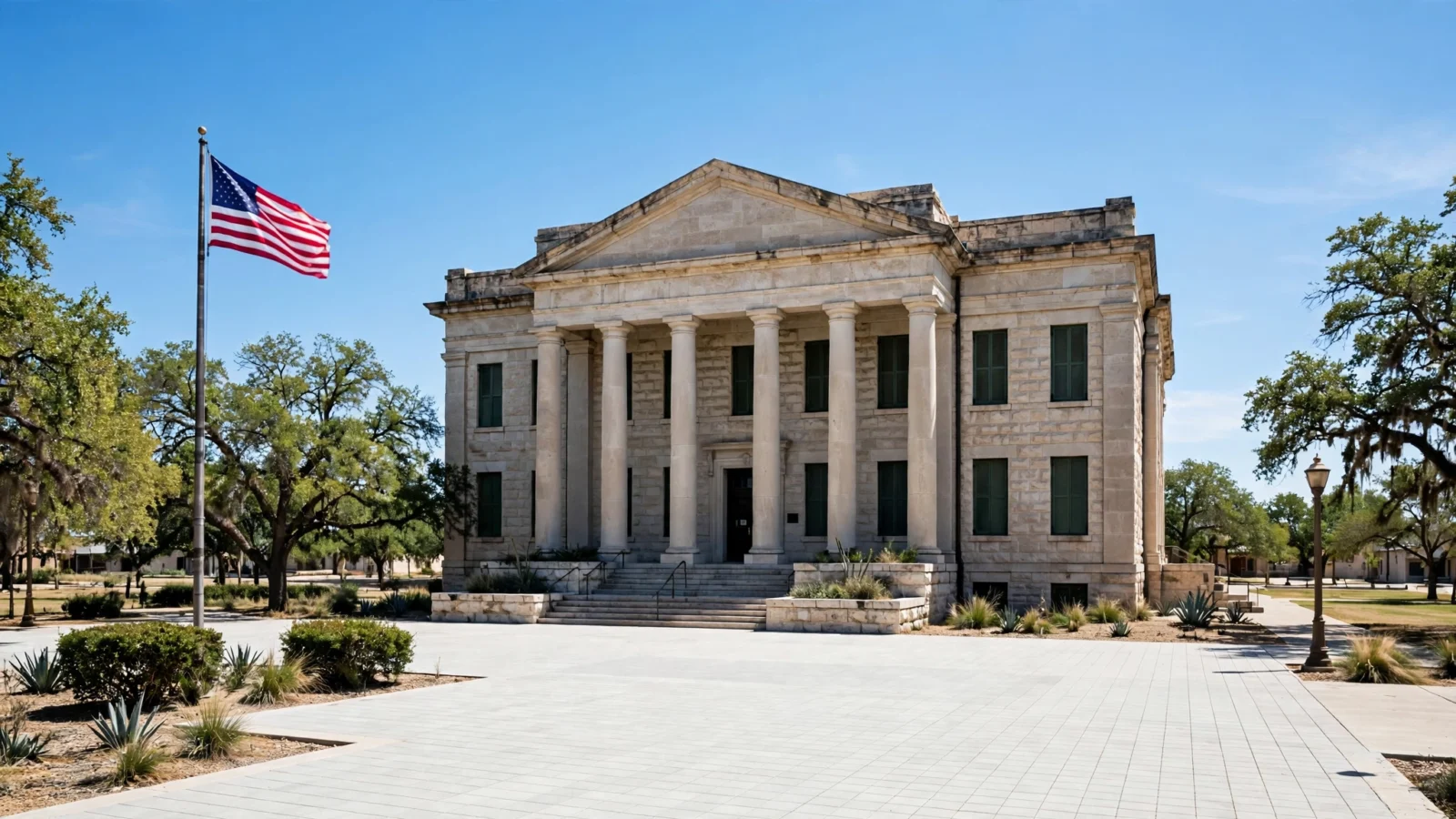 A stone courthouse building with tall columns and an American flag in front