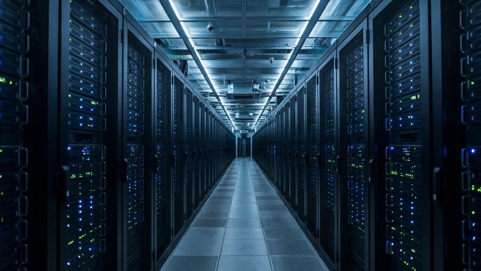 Rows of server racks with glowing blue indicator lights in a dark data center aisle.