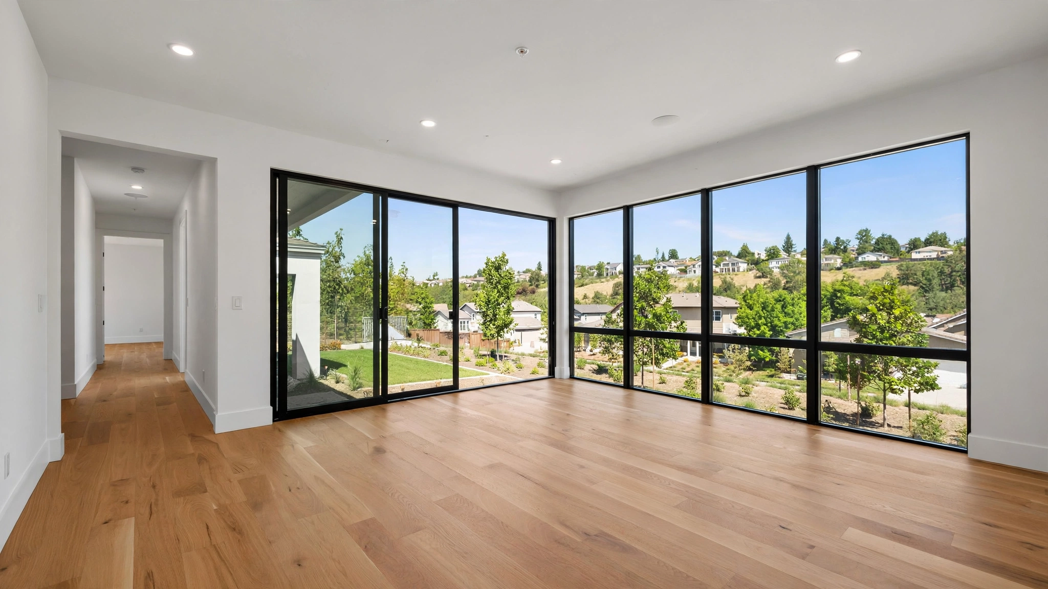 The empty interior of a newly built home with hardwood floors and large windows