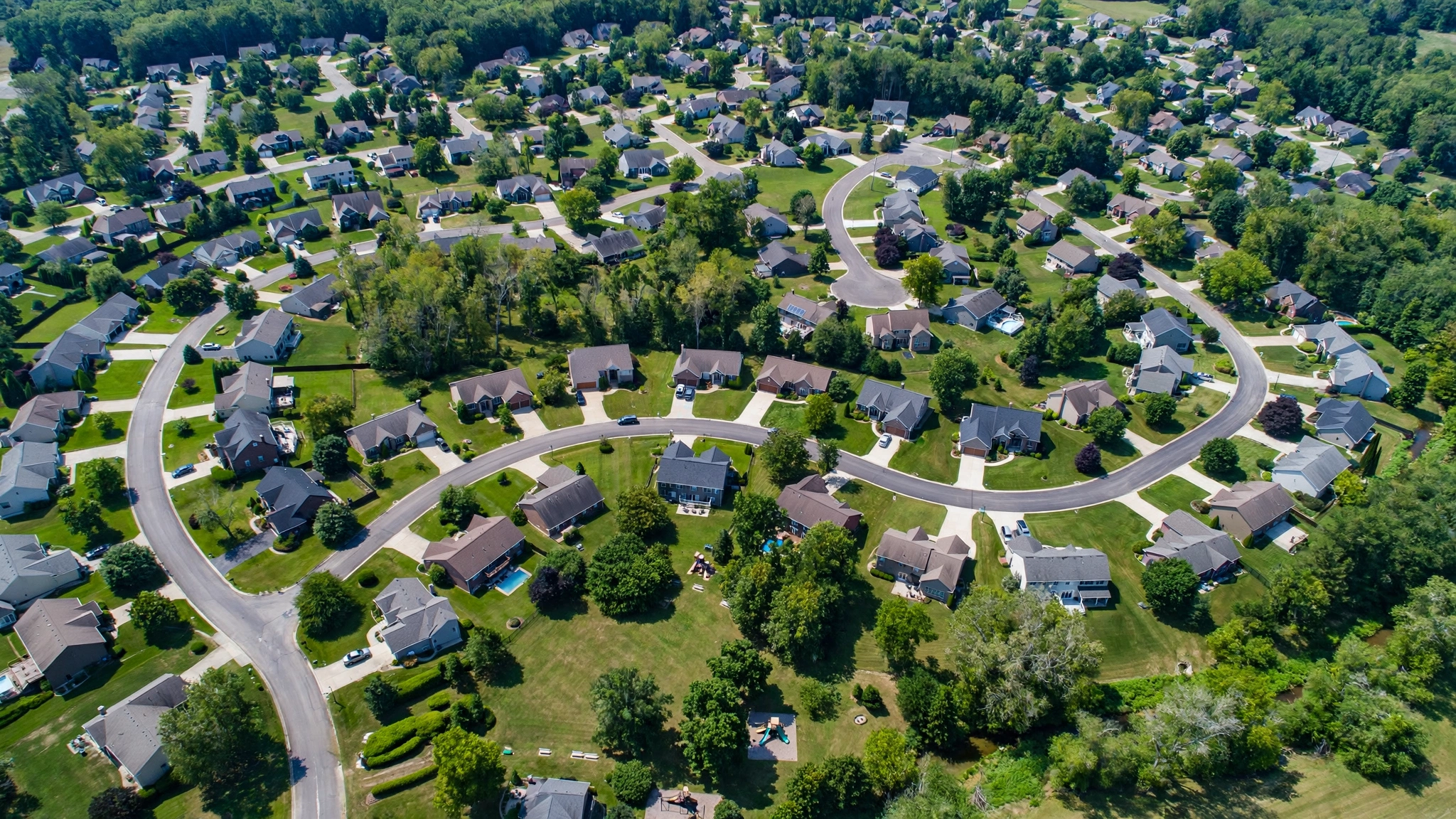 An aerial view of a suburban neighborhood with winding streets and green lawns