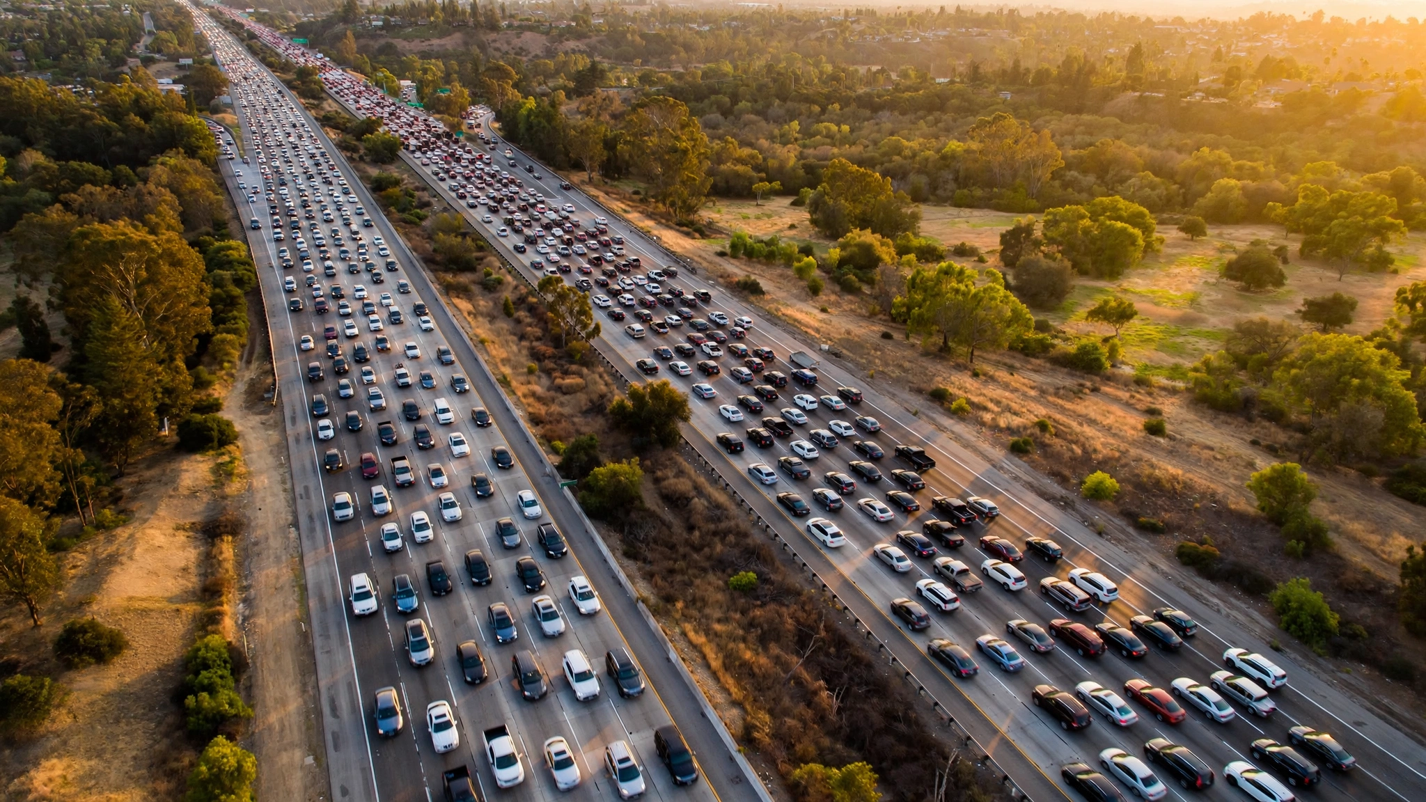An aerial view of heavy traffic on a multi-lane highway in golden evening light.