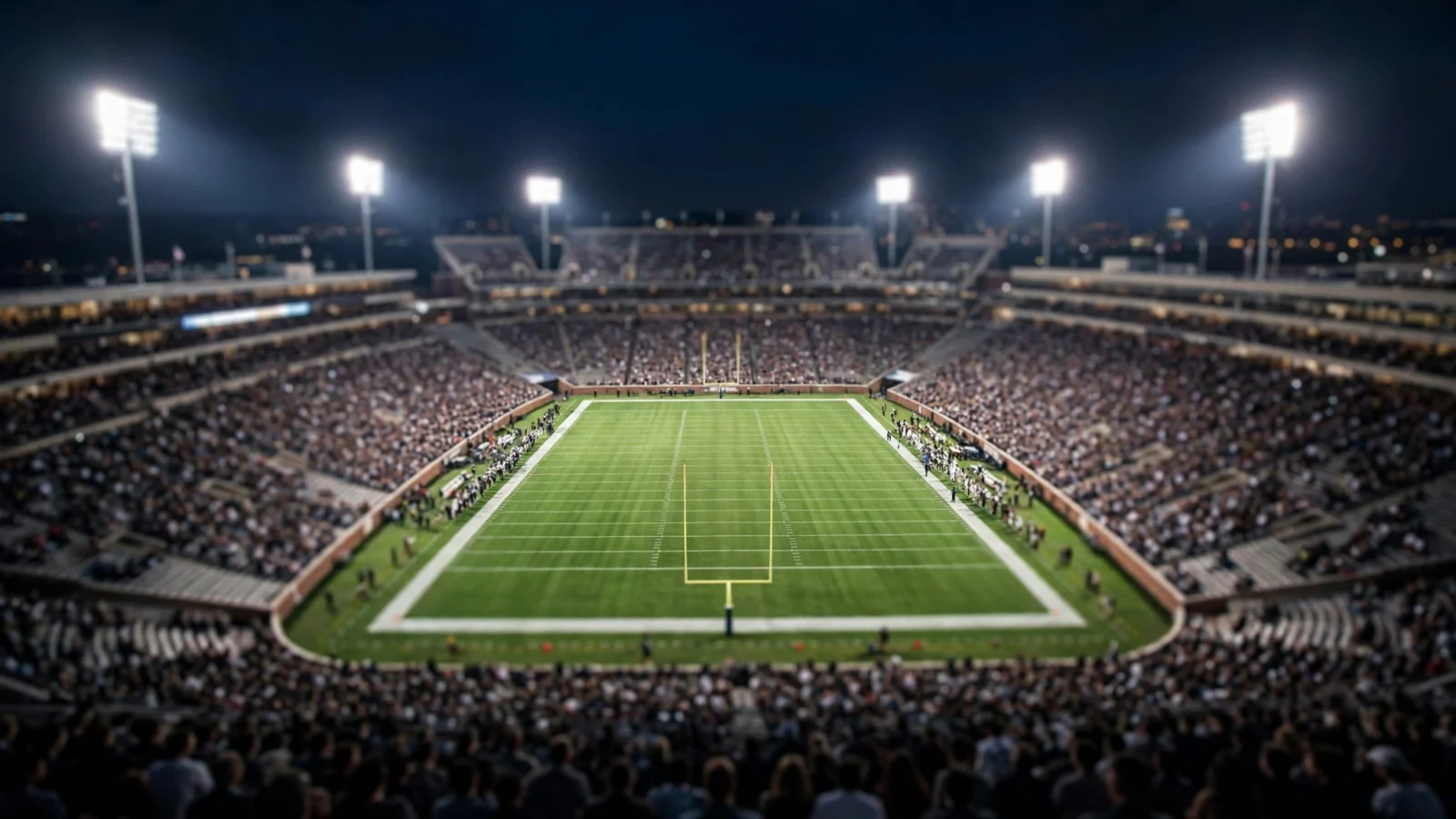 A college football stadium lit by floodlights at night with a crowded stand