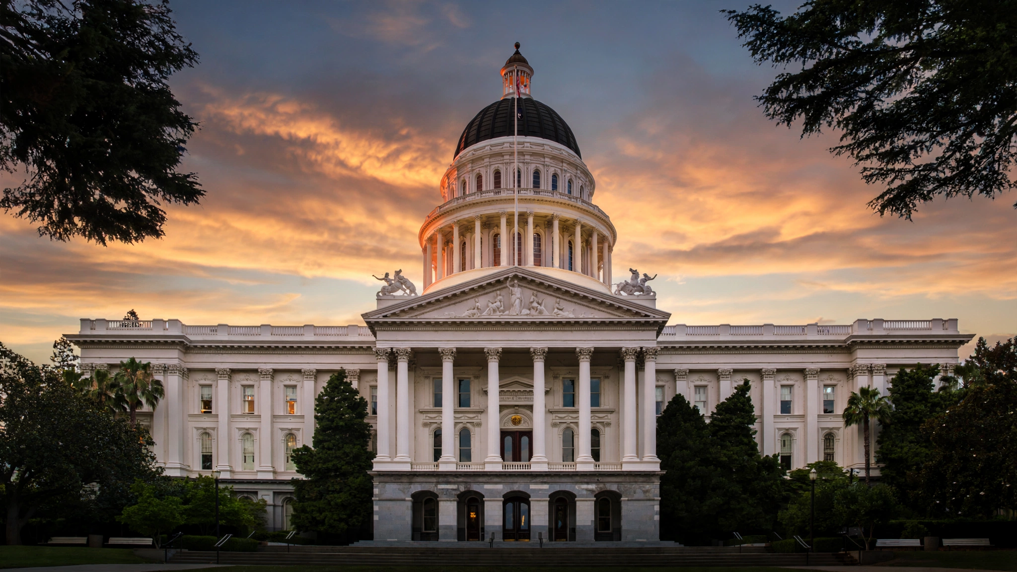 The California state capitol building at dusk under an orange sky