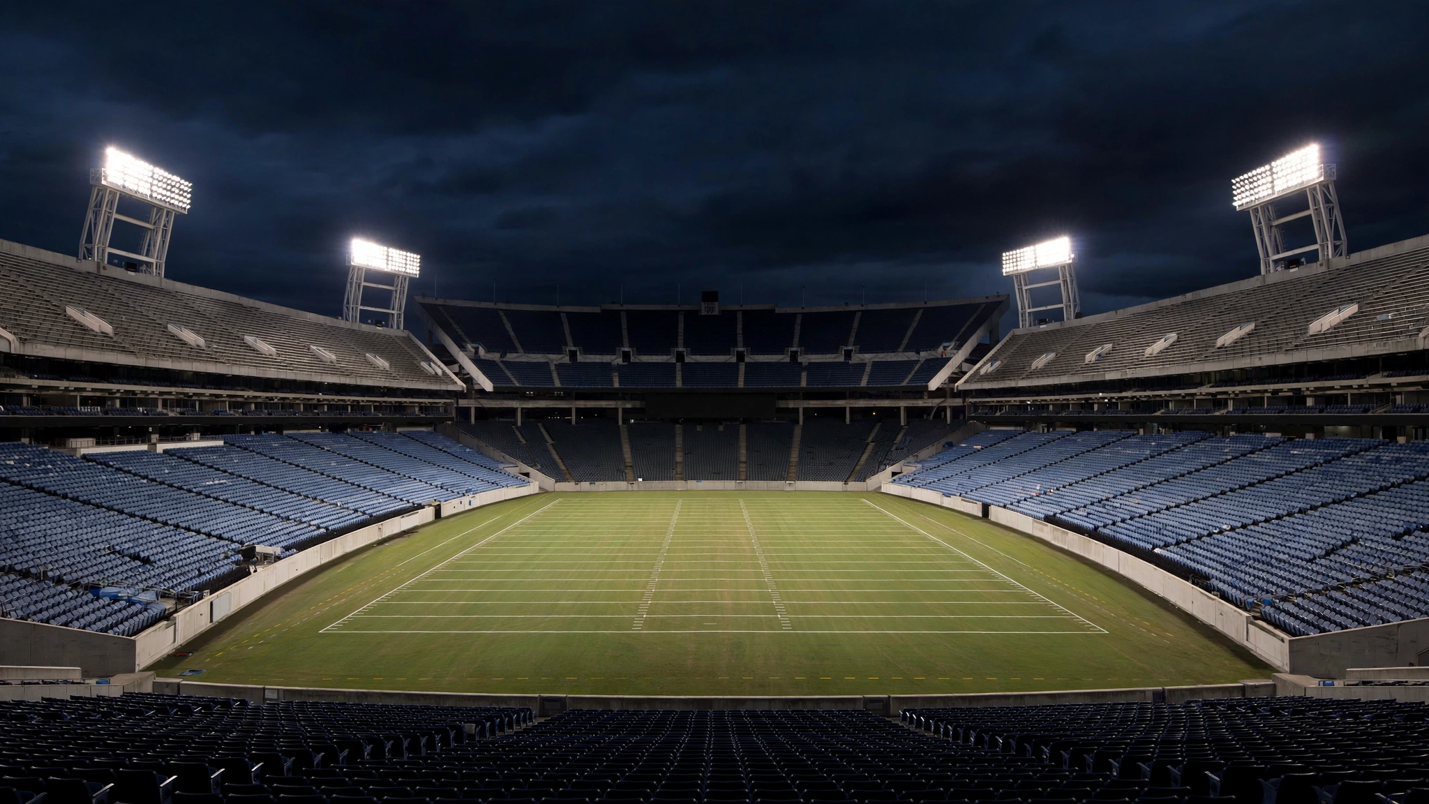 An empty football stadium at night with the field lit