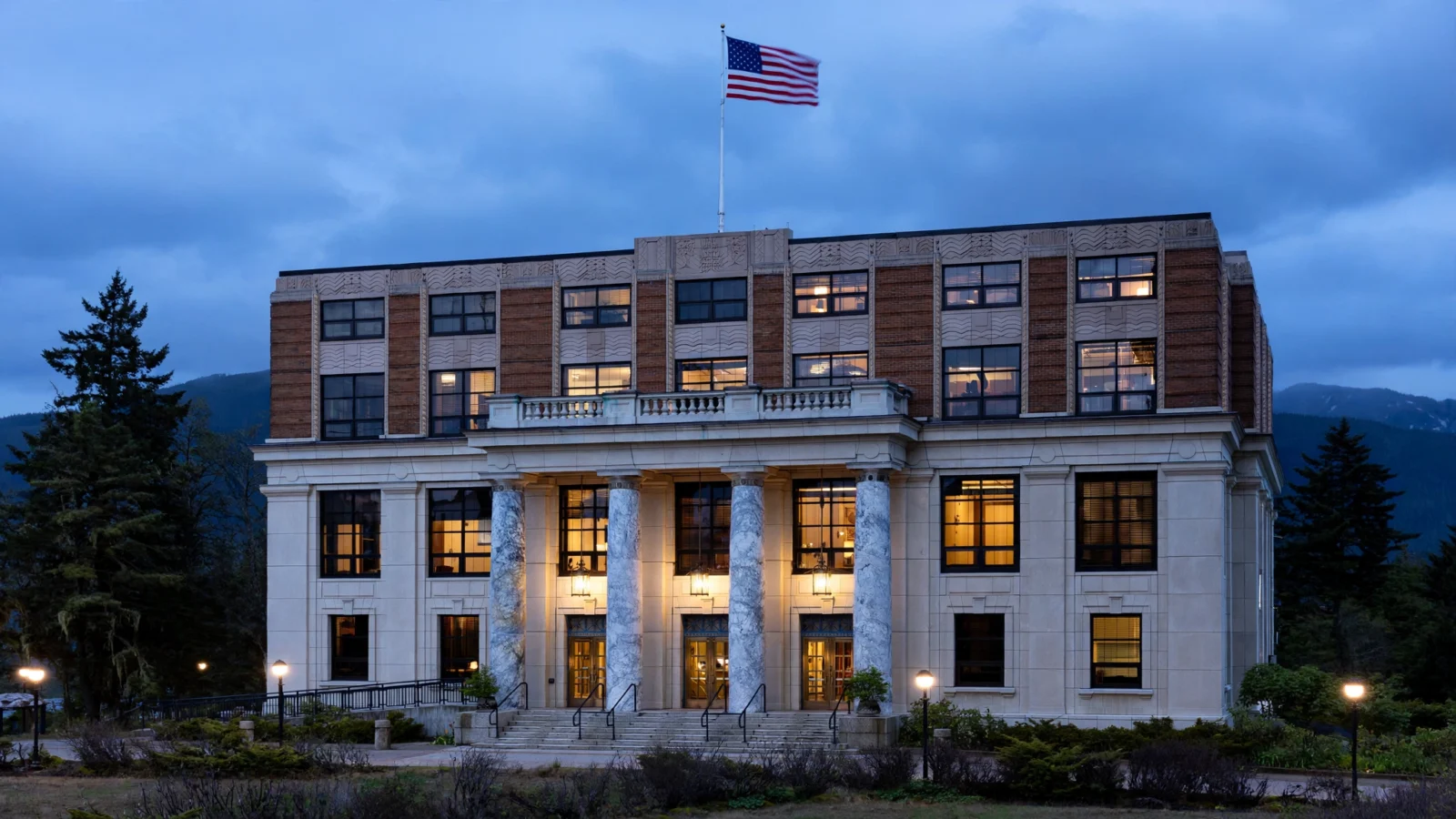 The Alaska State Capitol building in Juneau at dusk with the American flag flying from the roof