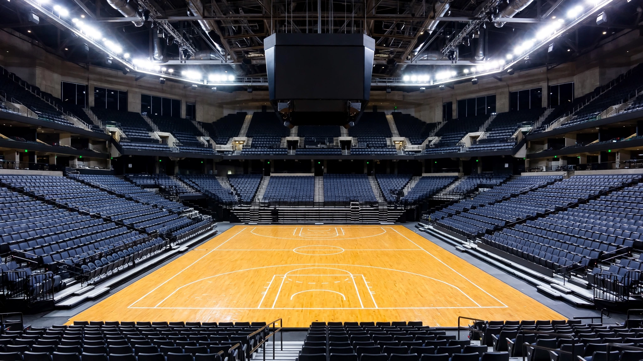An empty professional basketball arena at night with the court lit by spotlights