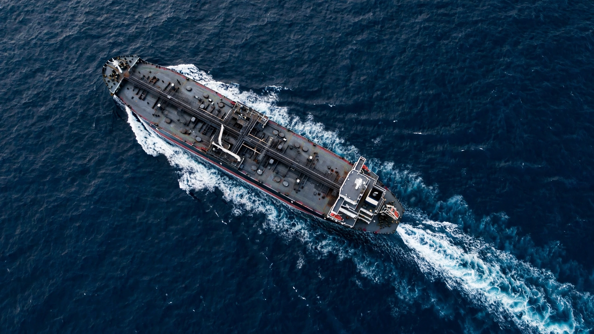 Aerial view of a tanker ship leaving a wake on dark blue ocean water