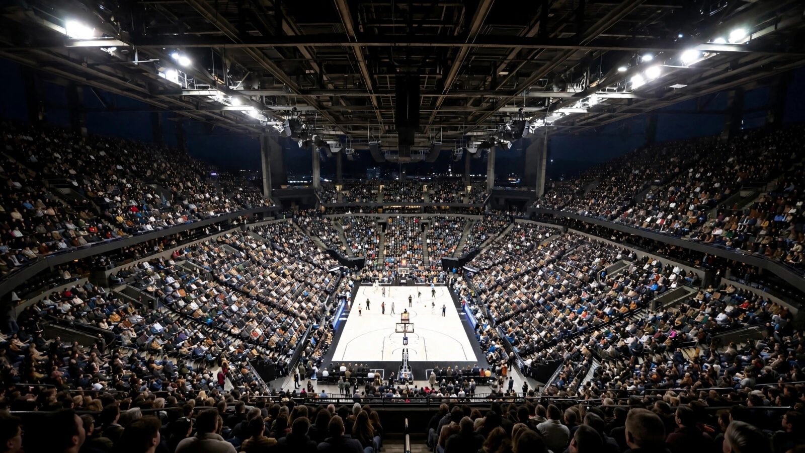 A packed basketball arena during a playoff game at night, with a full crowd in the stands and players on the court.