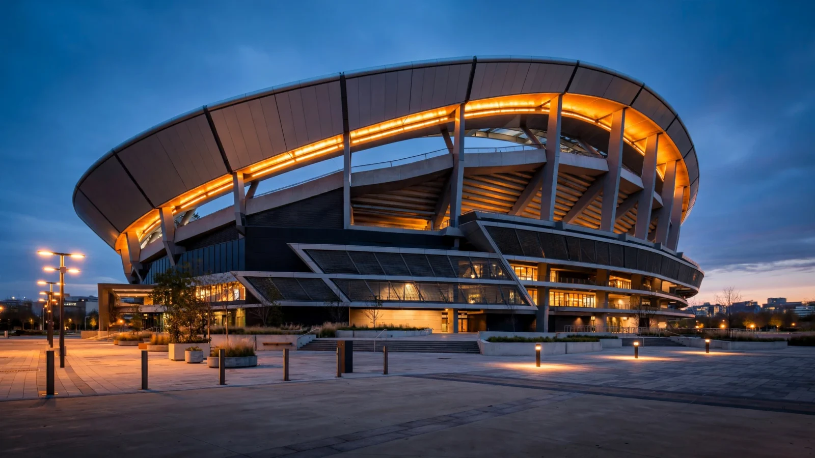 Exterior of a modern baseball stadium at dusk with the lights glowing over an empty plaza